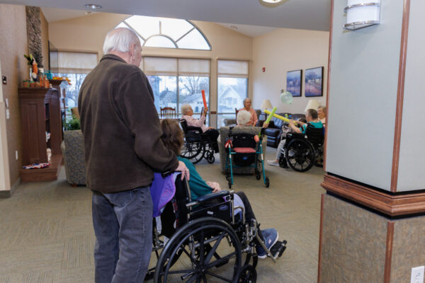 Older adults in wheelchairs participating in a group activity in a shared lounge, representing long-term care support similar to Westhaven Community.