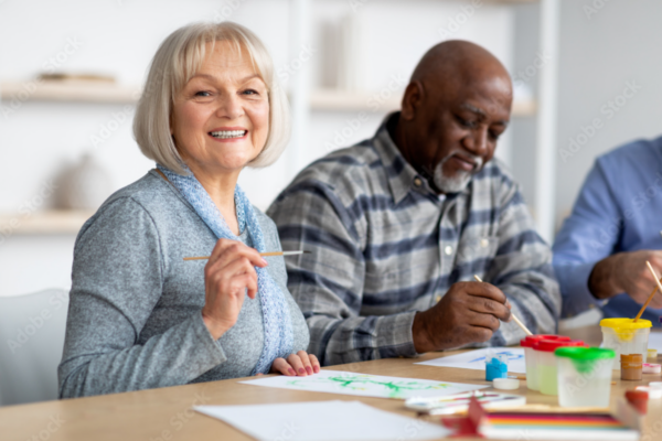 Older adults participating in a painting activity, representing social and recreational programs in assisted living communities similar to Boone, Iowa.