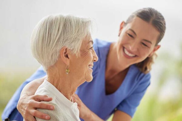 Adult caregiver and older adult sitting together and embracing, representing supportive assisted living care similar to communities in Boone, Iowa.