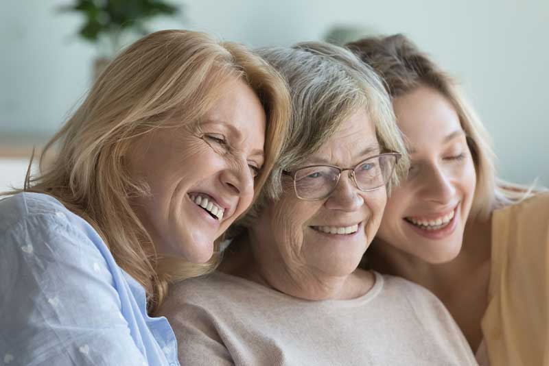 Older adults sitting closely together and looking at a screen, representing connection and relationships similar to Westhaven Community in Boone, Iowa.