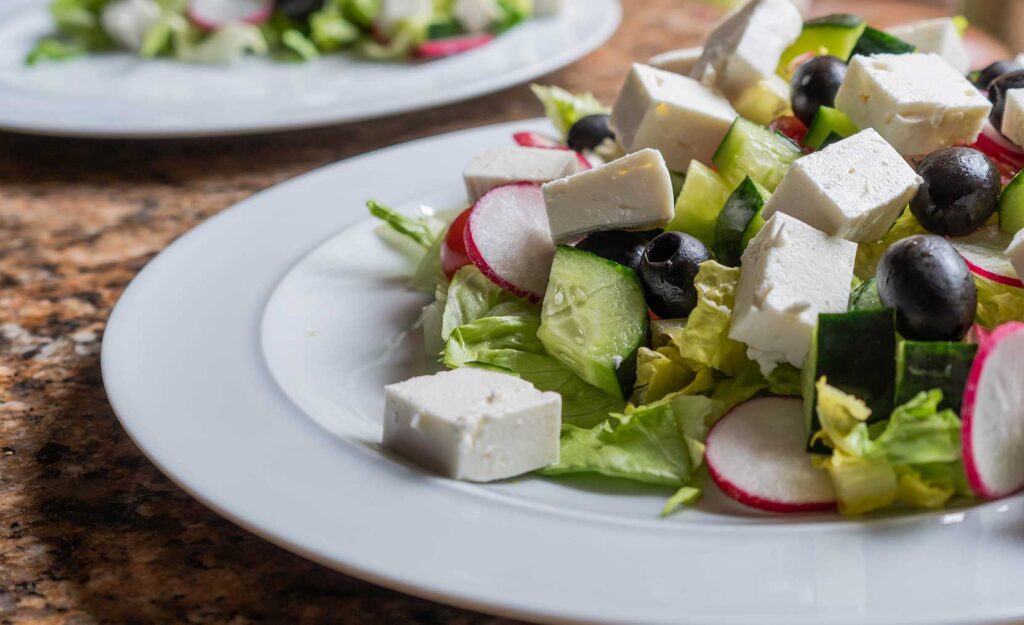 Fresh salad with lettuce, cucumber, olives, radishes, and cheese on a plate, representing nutritious meals in long-term care communities similar to Westhaven Community.
