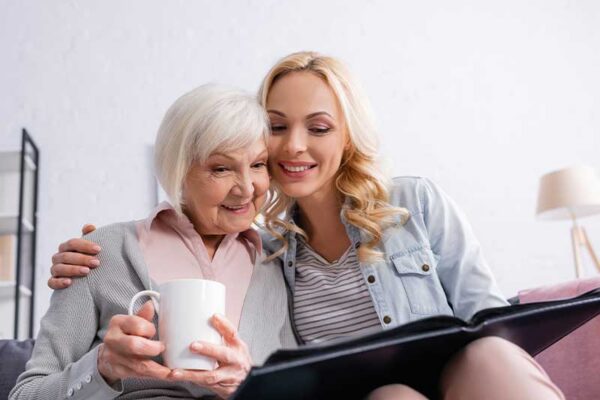 Older adult sitting with a companion and looking through a book together, representing supportive long-term care similar to Westhaven Community.