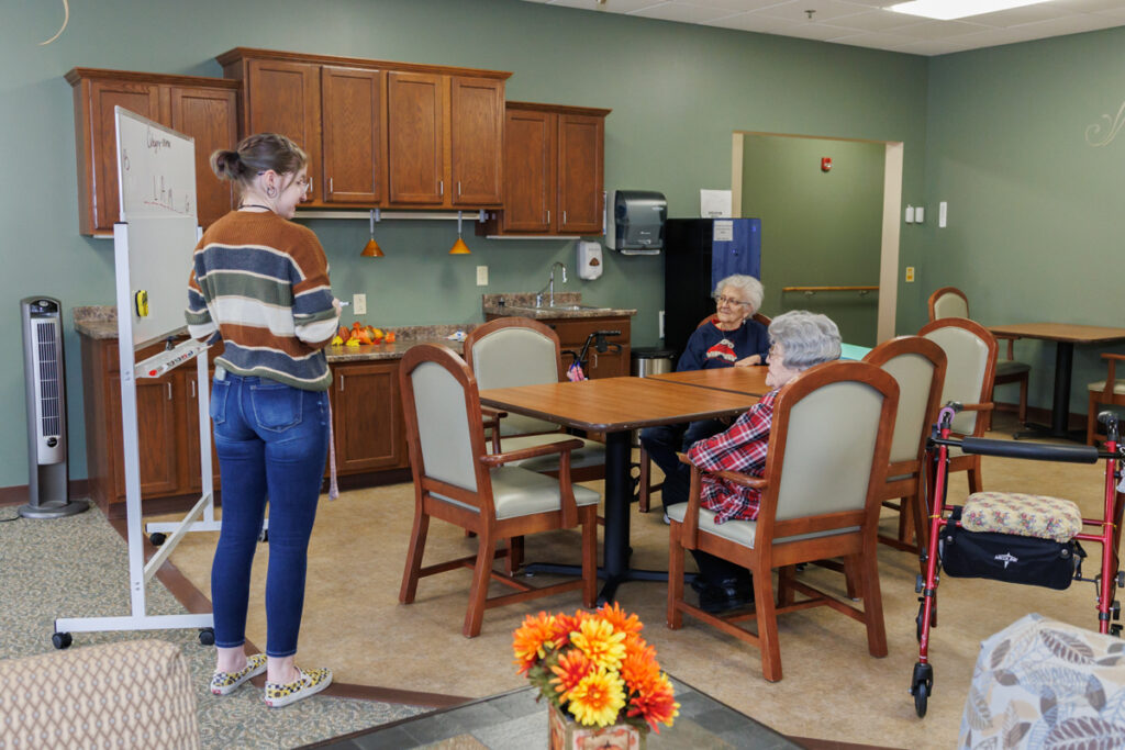 Staff member leading an activity with residents at Westhaven Community in Boone, Iowa in a shared dining and activity space.