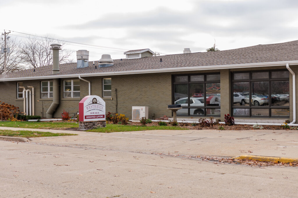Westhaven Community assisted living building exterior in Boone, Iowa with entrance sign, windows, and landscaped grounds.