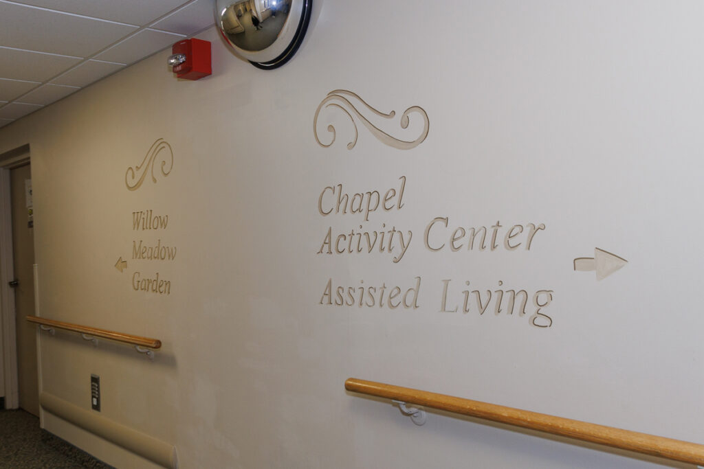 Hallway at Westhaven Community in Boone, Iowa with directional wall signage to chapel, activity center, assisted living, and garden areas.